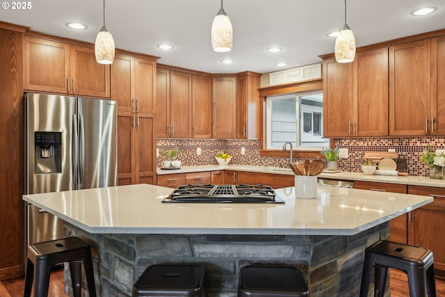 kitchen featuring a breakfast bar, stainless steel fridge, gas stovetop, and brown cabinetry