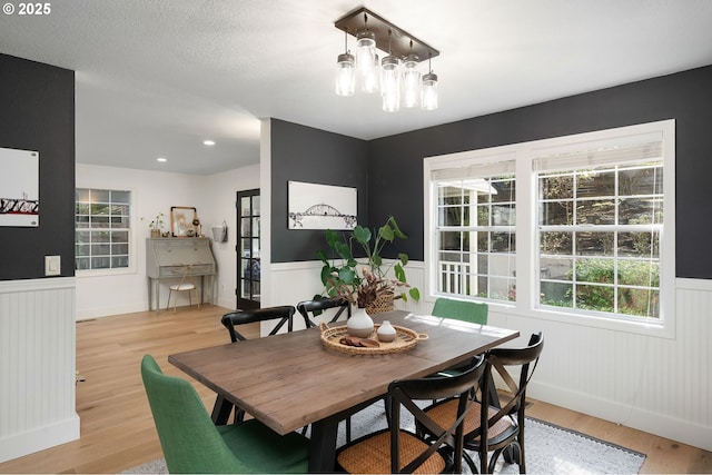 dining room featuring plenty of natural light, baseboards, a wainscoted wall, and light wood-type flooring