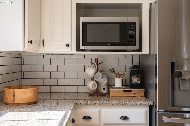 kitchen with decorative backsplash, stainless steel appliances, and white cabinets