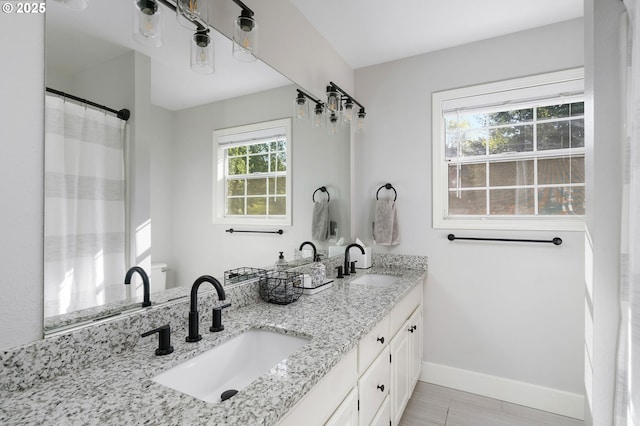 bathroom with baseboards, a sink, and double vanity