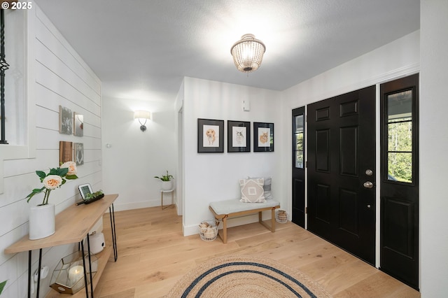 foyer featuring baseboards, a notable chandelier, and light wood-style flooring