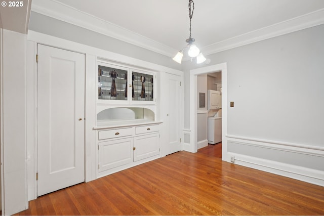 unfurnished dining area with washer / dryer, ornamental molding, and wood finished floors