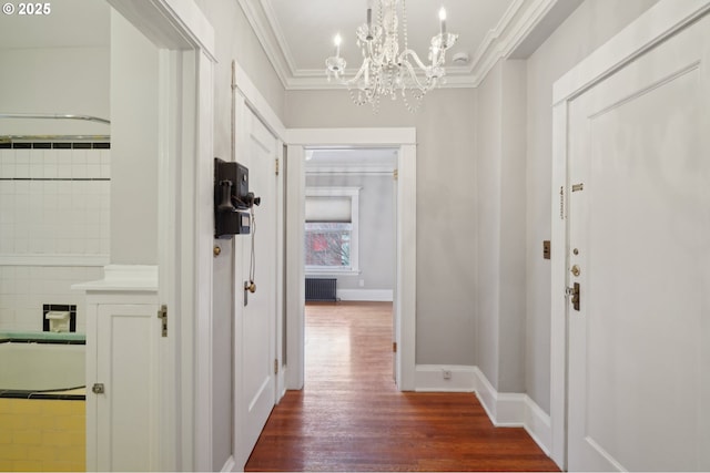 hallway featuring ornamental molding, radiator, baseboards, dark wood finished floors, and a notable chandelier