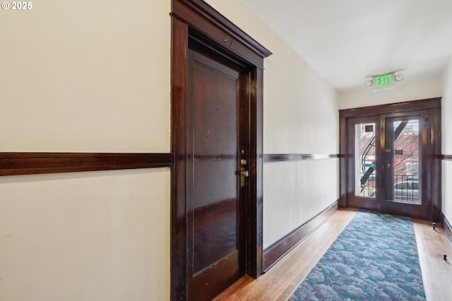 foyer entrance featuring baseboards, french doors, and light wood-type flooring