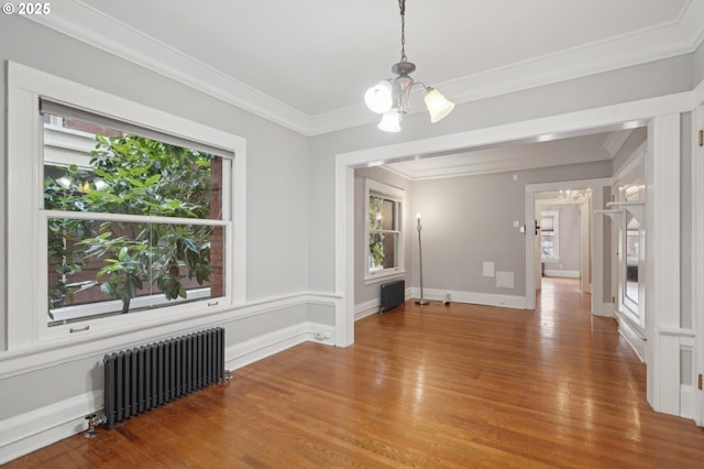 unfurnished dining area with an inviting chandelier, ornamental molding, radiator heating unit, and wood finished floors