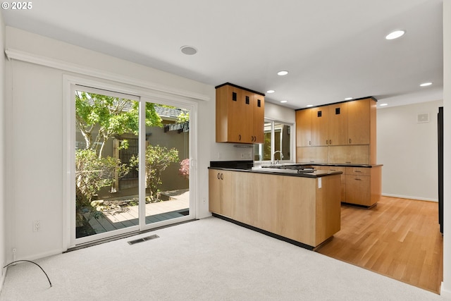 kitchen with dark countertops, recessed lighting, baseboards, a peninsula, and visible vents
