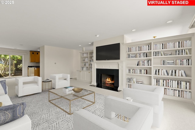 living area with carpet floors, recessed lighting, a fireplace with flush hearth, and built in features