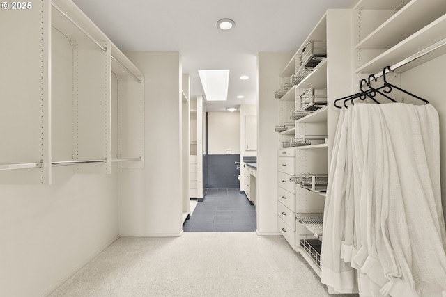 walk in closet featuring carpet floors, tile patterned flooring, and a skylight