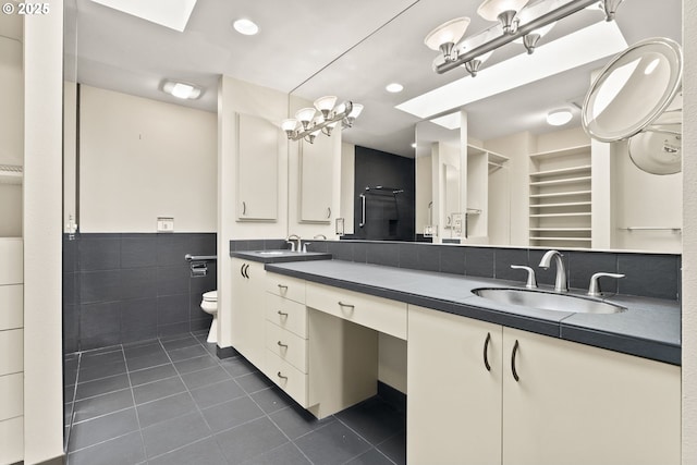 bathroom with a sink, double vanity, toilet, tile patterned floors, and tile walls