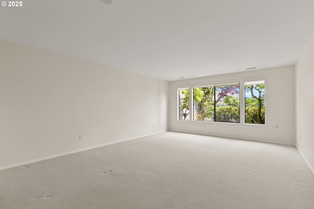unfurnished room featuring baseboards, visible vents, and light colored carpet