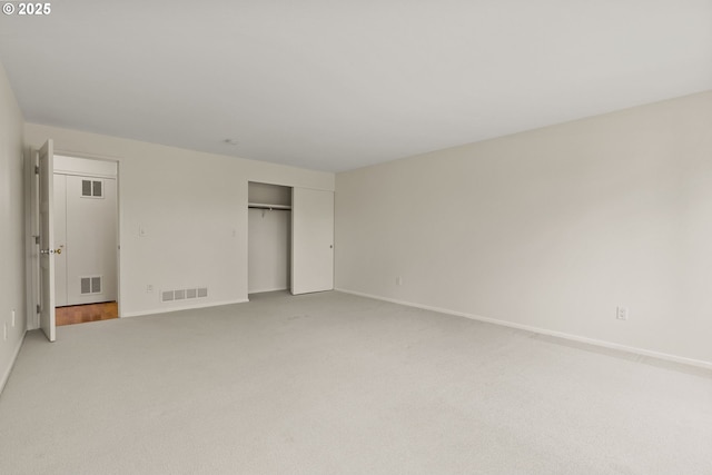 unfurnished bedroom with visible vents, baseboards, a closet, and light carpet