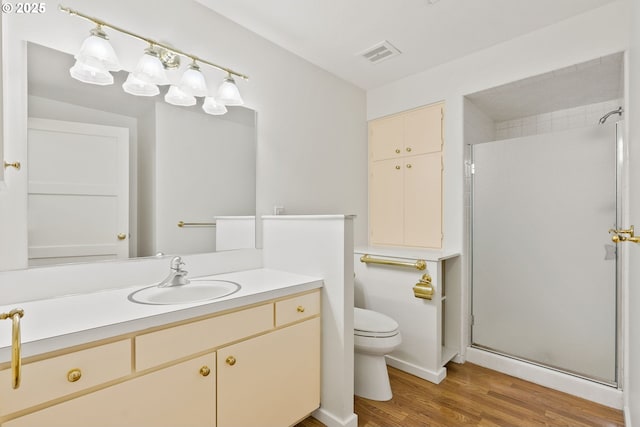 full bath featuring vanity, toilet, a shower stall, wood finished floors, and visible vents