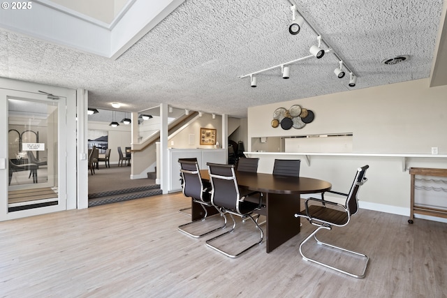 dining area with track lighting, stairs, baseboards, wood finished floors, and visible vents