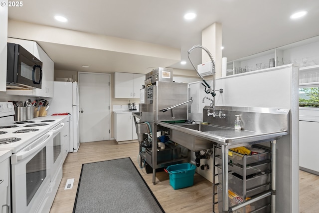 kitchen featuring black microwave, white range with electric cooktop, light wood finished floors, and white cabinetry
