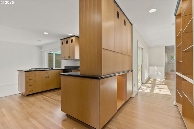 kitchen with light wood-type flooring, recessed lighting, a peninsula, and dark countertops