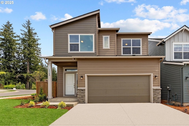 view of front facade featuring an attached garage, a front yard, driveway, and stone siding