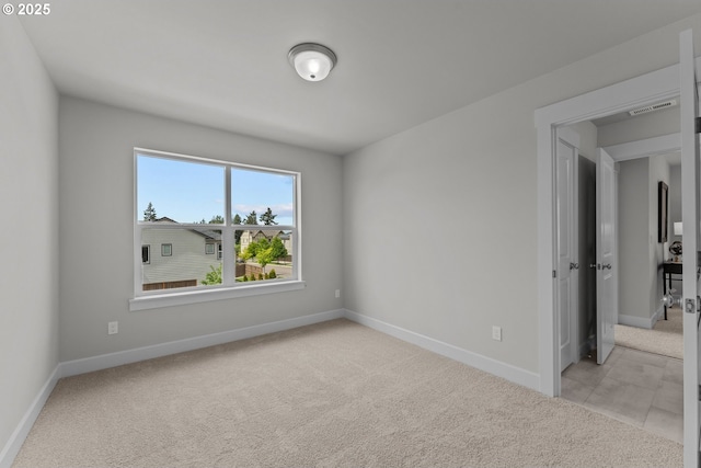 empty room featuring baseboards, light colored carpet, and visible vents