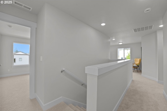 corridor with baseboards, light carpet, an upstairs landing, and visible vents