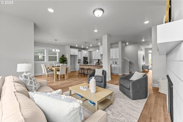 living area with an inviting chandelier, recessed lighting, baseboards, and light wood-type flooring