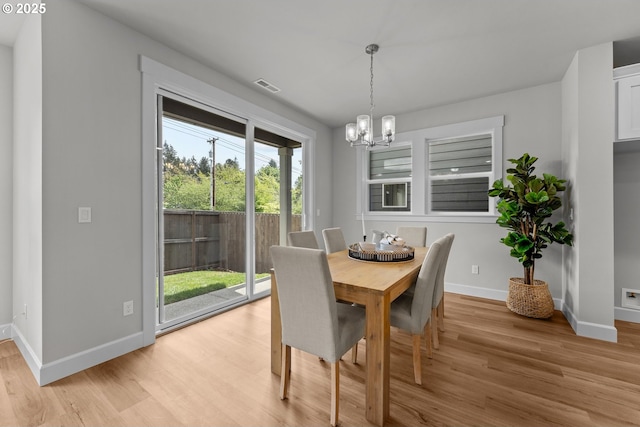 dining room with baseboards, a notable chandelier, light wood finished floors, and visible vents