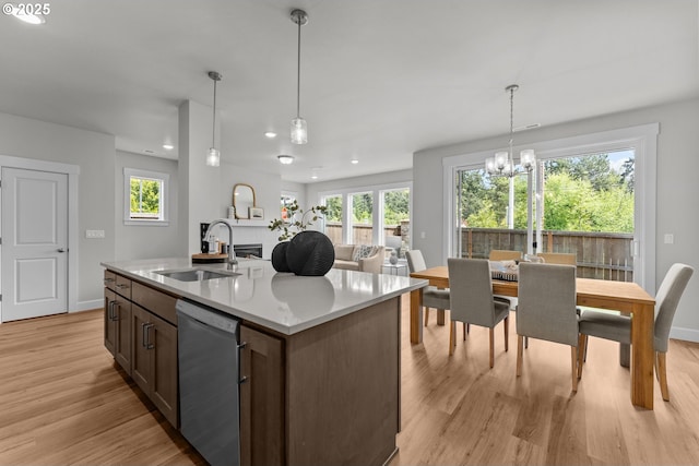 kitchen with an inviting chandelier, plenty of natural light, light wood-type flooring, a sink, and dishwasher