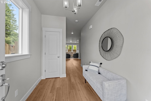 hall featuring visible vents, baseboards, a chandelier, light wood-style floors, and recessed lighting