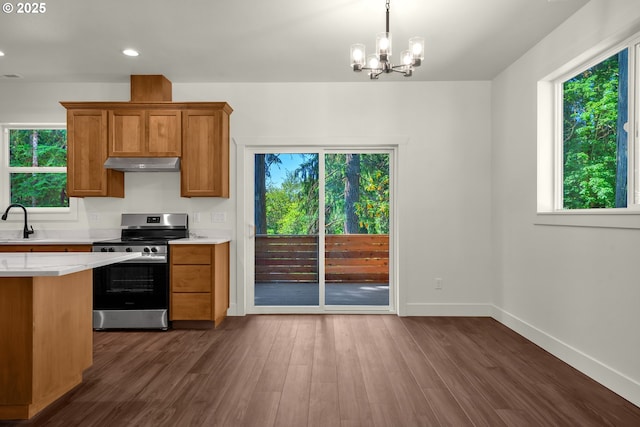 48438 E Meadow Way, Oakridge, OR 97463 - kitchen with stainless steel electric range oven, under cabinet range hood, light countertops, brown cabinetry, and plenty of natural light
