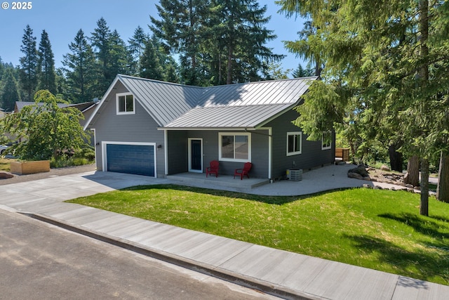 48438 E Meadow Way, Oakridge, OR 97463 - view of front of house featuring a standing seam roof, a front yard, concrete driveway, an attached garage, and a metal roof