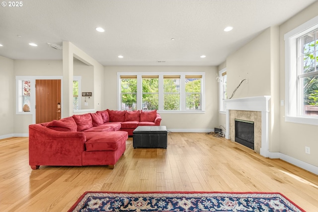living room featuring a high end fireplace, baseboards, recessed lighting, and hardwood / wood-style flooring