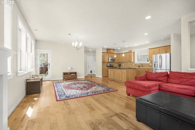 living room with baseboards, recessed lighting, light wood-style flooring, and a chandelier