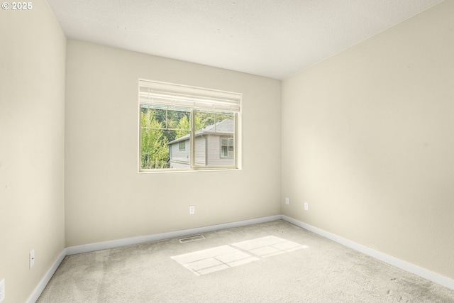 carpeted empty room featuring baseboards and visible vents