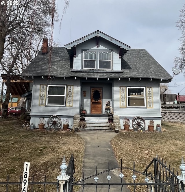 bungalow with a fenced front yard, a chimney, and a shingled roof