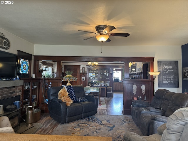 living room with a wealth of natural light, wood finished floors, and ceiling fan with notable chandelier