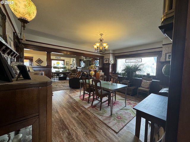 dining area featuring a notable chandelier, wood finished floors, and a textured ceiling