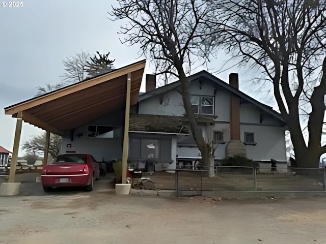 view of front facade featuring an attached carport, concrete driveway, and a chimney