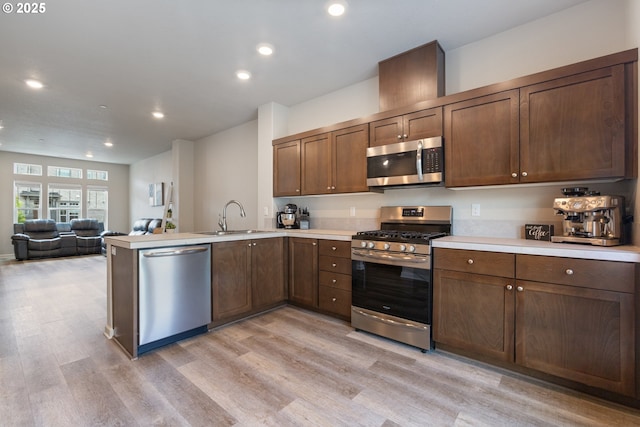 11449 SW Mont Blanc St, Wilsonville, OR 97070 - kitchen with stainless steel appliances, a sink, light wood-style flooring, a peninsula, and light countertops