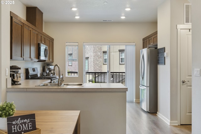 11449 SW Mont Blanc St, Wilsonville, OR 97070 - kitchen featuring stainless steel appliances, a peninsula, light wood-type flooring, a sink, and light countertops