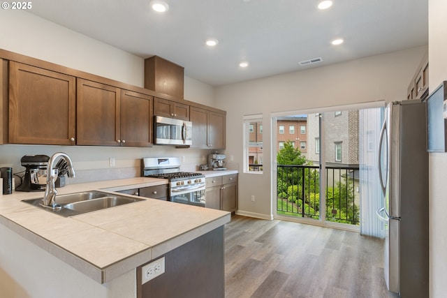 11449 SW Mont Blanc St, Wilsonville, OR 97070 - kitchen featuring appliances with stainless steel finishes, a sink, light countertops, light wood-style floors, and recessed lighting