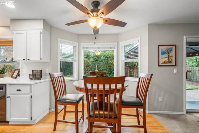 dining space featuring light wood-type flooring, a ceiling fan, and baseboards