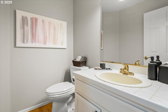 half bath featuring toilet, baseboards, wood finished floors, and vanity