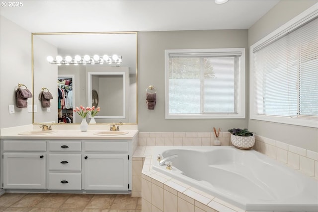 full bath with double vanity, a garden tub, a sink, and tile patterned floors