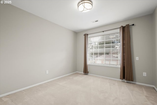 empty room featuring visible vents, baseboards, and light colored carpet