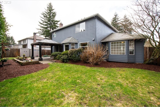 rear view of property featuring a lawn, a patio, a chimney, fence, and a gazebo