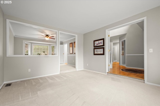 empty room with visible vents, baseboards, ceiling fan, carpet, and crown molding