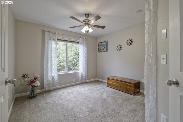 carpeted empty room featuring ceiling fan and baseboards
