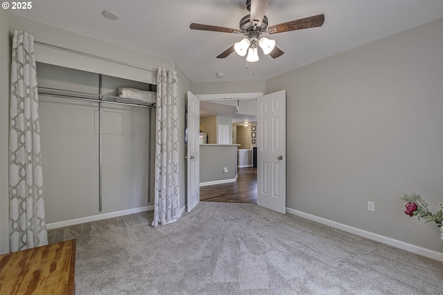 unfurnished bedroom with baseboards, ceiling fan, carpet, and a closet