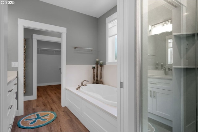 83591 Sauter Dr, Florence, OR 97439 - full bathroom featuring vanity, a garden tub, wood finished floors, a walk in closet, and an enclosed shower