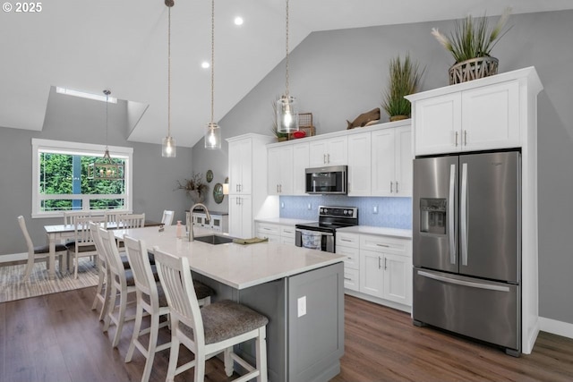 83591 Sauter Dr, Florence, OR 97439 - kitchen featuring stainless steel appliances, high vaulted ceiling, dark wood-style floors, an island with sink, and white cabinetry