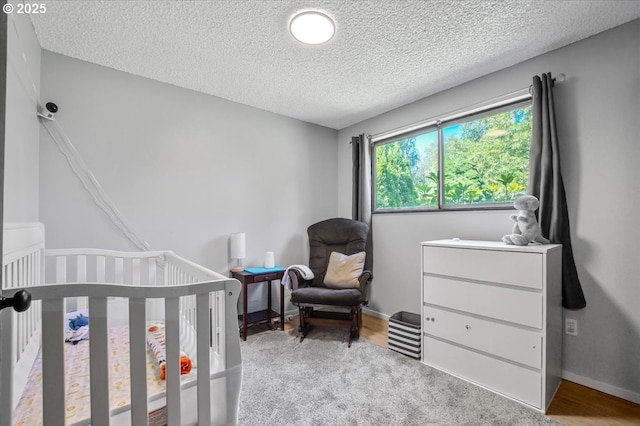 9532 SW Whitford Ln, Beaverton, OR 97008 - bedroom featuring a textured ceiling, a nursery area, baseboards, and wood finished floors