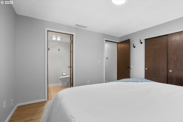 9532 SW Whitford Ln, Beaverton, OR 97008 - bedroom with a closet, light wood-style flooring, baseboards, connected bathroom, and a textured ceiling